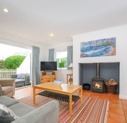 A living room with sofas a coffee table a burning wood stove and a television at Bryher in Trebetherick near Polzeath