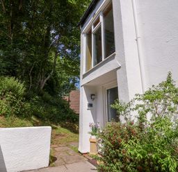 An exterior view of a white building entrance with plants and trees nearby at 37 Tamar in St Ann's Chapel near Callington