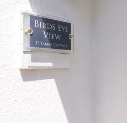 A close up of a wall plaque reading Birds Eye View 37 Tamar Cottage on a white textured wall at 37 Tamar St Ann's Chapel near Callington