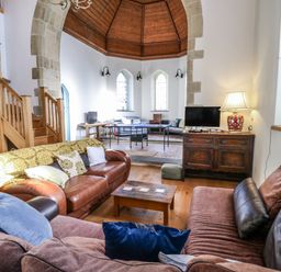 A living room with a sofa and staircase at Church Llygad Y Dyffryn Sarnau near Brynhoffnant