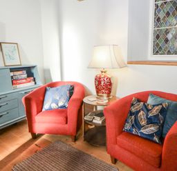 A living room with two red armchairs and a lamp at Church Llygad Y Dyffryn Sarnau near Brynhoffnant