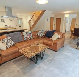 An open plan living room with a brown sectional sofa and wooden coffee table near a kitchen and dining area at The Grove in Wolfsdale near Haverfordwest
