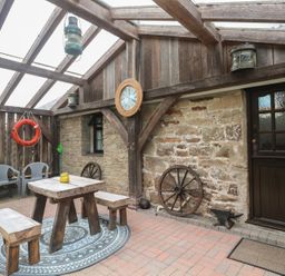 An outdoor seating area with a table and chairs at Horseshoe Cottage near Holywell Bay