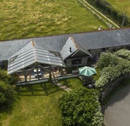 A patio with seating area and parasol at Horseshoe Cottage near Holywell Bay