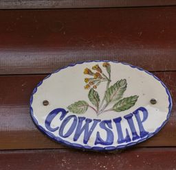 An oval ceramic sign with a flower design and the word Cowslip on a wooden surface at Cowslip in Saltburn-By-The-Sea