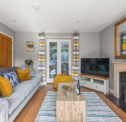 A living room with a sofa and cushions a coffee table a television and a fireplace at Seascape in Kingsand