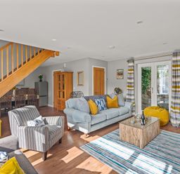 A living room with sofas a striped armchair a coffee table and a dining area near stairs at Seascape Kingsand