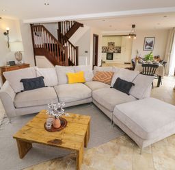 A living room with a beige sectional sofa and wooden coffee table near a staircase and an open kitchen and dining area at Little Acre in Church Lench near Harvington