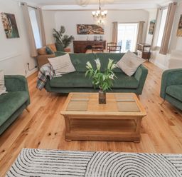 A living room with green sofas wooden coffee table and dining area at Tremornah Lamorna
