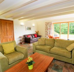 A living room with sofas, a table, and a window at Bryn Isaf near Swyddffynnon near Pontrhydfendigaid