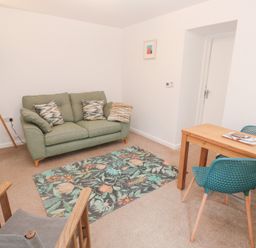 A living room with a sofa, table, and lamp at Mys Hedra Farm in St Buryan