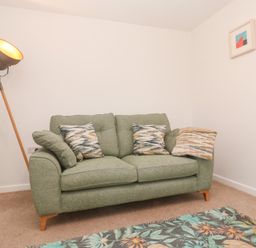A living room with a sofa and floor lamp at Mys Hedra Farm St Buryan