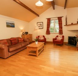 A living room with a brown sofa and red armchairs around a wooden coffee table at Blue Hill House in Ambleside