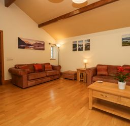 A living room with two brown sofas a wooden coffee table with a plant and landscape pictures on walls at Blue Hill House in Ambleside