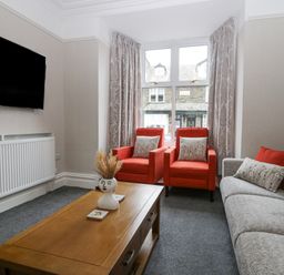A living room with two red armchairs a gray sofa a wooden coffee table and a wall-mounted tv at Park Beck 3 in Windermere