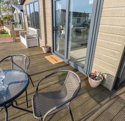 An outdoor deck with a glass table and two wicker chairs at Brocklebank Lodge 35 in High Hesket near Armathwaite