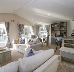 A living room with sofas dining table chairs and shelving unit at The Three Bears Lodge Coniston Drive 11 South Lakeland Leisure Village near Warton