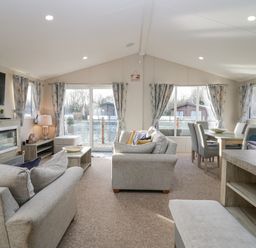 A living room with sofas, a TV, a fireplace, a coffee table, and a dining table with chairs at The Three Bears Lodge Coniston Drive 11 South Lakeland Leisure Village near Warton