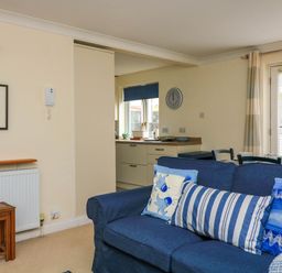 A living room with a blue sofa and pillows next to a dining table and an open kitchen at 8 Dartmouth House in Dartmouth
