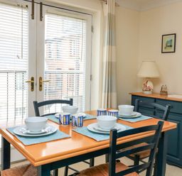 A dining room with a wooden table set for four and dark blue chairs at 8 Dartmouth House in Dartmouth