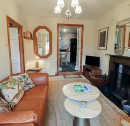 A living room with a brown leather sofa and coffee tables near a fireplace and a television at Riverbank At Stepping Stones in Rydal