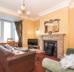 A living room with brown and green sofas a wooden coffee table a fireplace and a TV at Claremount in Alnmouth