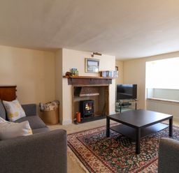A living room with two gray sofas a black coffee table a fireplace and a bay window seat at 30 Fleet Street in Beaminster
