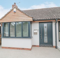 Front entrance of a house with a blue door and windows with shutters at Orchard Leigh in North Petherton