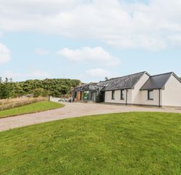 A single-story house with white walls and a gray roof on a grassy property with a gravel driveway at Ballyness Bay in Killult Upper near Gortahork County Donegal