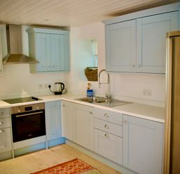 A kitchen with blue cabinets a stainless steel oven and fridge and a sink at Windrush in Burford