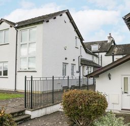 An exterior view of white residential buildings with multiple windows a black metal railing and a paved walkway at Ramblers Lodge in Bowland Bridge near Bowness-On-Windermere Lake District
