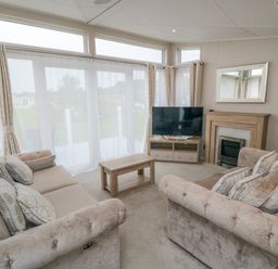 A living room with two sofas a coffee table a television and a fireplace at Finch 65 in Cayton Bay