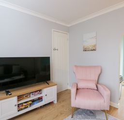A living room with a television and a pink chair at 20 Honeycroft in Bourton-On-The-Water