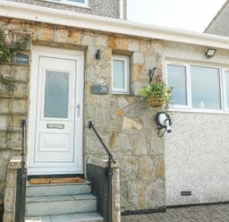 Front entrance of a house with a white door stone steps and a hanging flower pot at Ty Copr in Amlwch