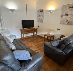 A living room with a sofa and TV at Woodside Cottage in Kerry