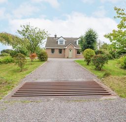 A house with a gravel driveway and trees on both sides at Knockbrack in Lonart near Killorglin County Kerry