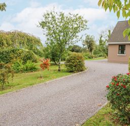 A gravel driveway surrounded by trees and bushes next to a house at Knockbrack in Lonart near Killorglin County Kerry