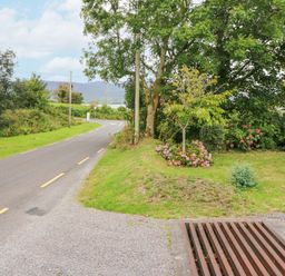 A road with yellow lines beside a grassy area with trees and flowers at Knockbrack in Lonart near Killorglin County Kerry