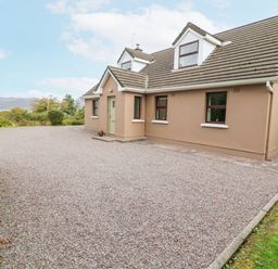A detached house with a gravel driveway and a hedge on the left side at Knockbrack in Lonart near Killorglin County Kerry