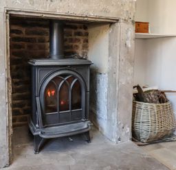 A fireplace with a wood burning stove and a basket of firewood at Field View in Ruswarp