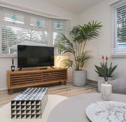 A living room with a television and plants at Cosy Corner White Cross Bay near Troutbeck Bridge