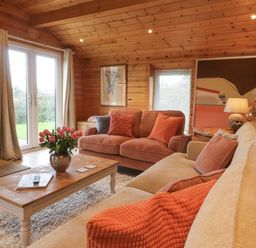 A living room with sofas cushions a coffee table with flowers a fireplace and wall art at Artisan Lodge in Longridge