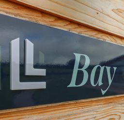 A close up of a sign with the word Bay on a wooden wall at Bay Ilfracombe