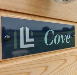 A close up of a sign reading Cove mounted on a wooden wall at Cove Lodge in Ilfracombe