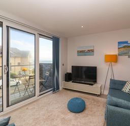A living room with sliding glass doors leading to a balcony with a table and chairs at 7 Warren Edge Close in Bournemouth