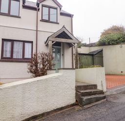 Exterior of a two-story house with a green front door and steps leading to the entrance at Cheriton in Pembroke Dock