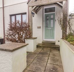 A front entrance with concrete paving plants and a green door at Cheriton in Pembroke Dock