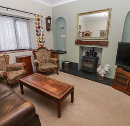 A living room with armchairs a coffee table a television and a fireplace at Cheriton in Pembroke Dock