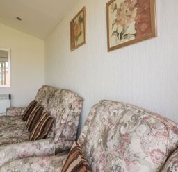 A living room with patterned sofas and cushions and framed floral wall art at Warren Cove near St Merryn