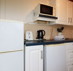 A kitchen corner with a microwave on a shelf a toaster a kettle and utensils in jars on a countertop near Hawker's Cove near St Merryn